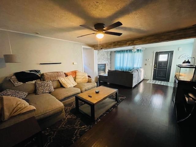 living room featuring beamed ceiling, dark hardwood / wood-style flooring, a textured ceiling, and ceiling fan