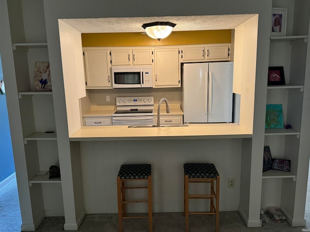 kitchen with sink, white cabinetry, carpet floors, and white appliances