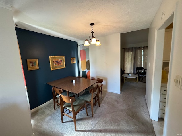 carpeted dining room featuring a notable chandelier and a textured ceiling