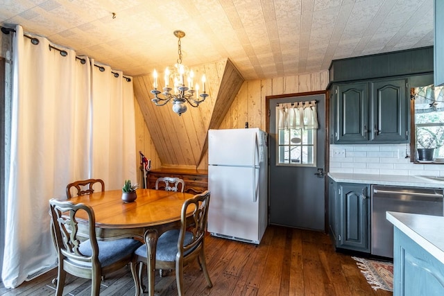 dining room featuring wood walls, an inviting chandelier, lofted ceiling, and dark hardwood / wood-style flooring