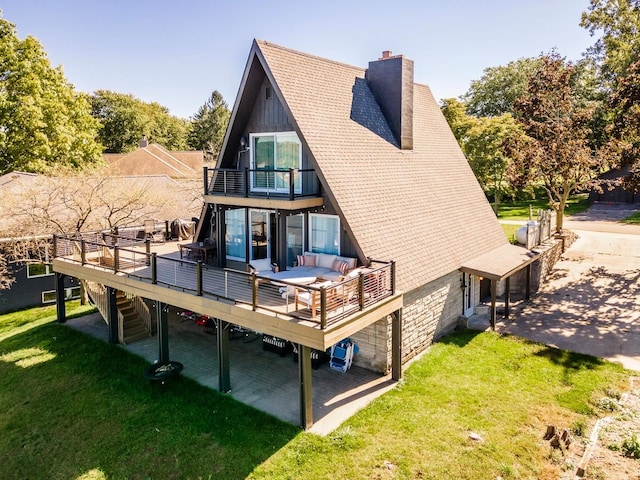 rear view of property featuring a balcony, a deck, and a yard