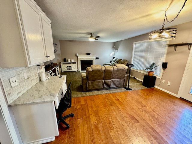 living room with a textured ceiling, hardwood / wood-style flooring, and ceiling fan