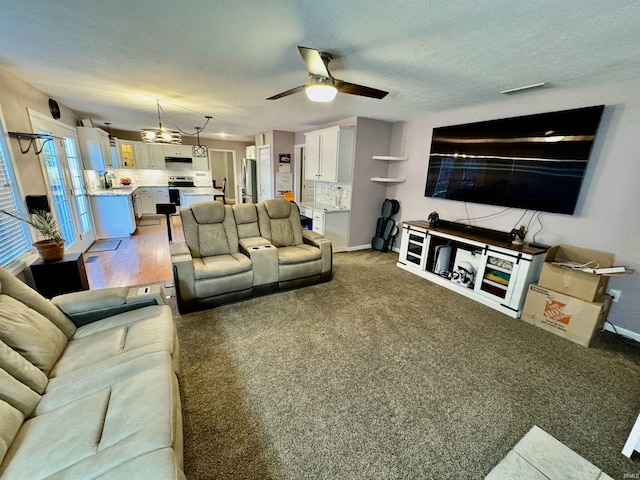 carpeted living room featuring ceiling fan and a textured ceiling