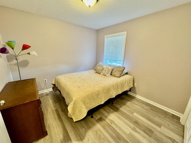 bedroom featuring light wood-type flooring and a textured ceiling