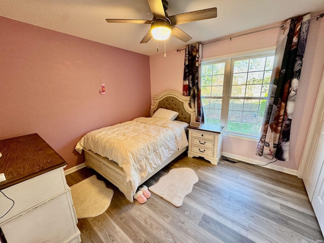 bedroom featuring multiple windows, hardwood / wood-style floors, and ceiling fan