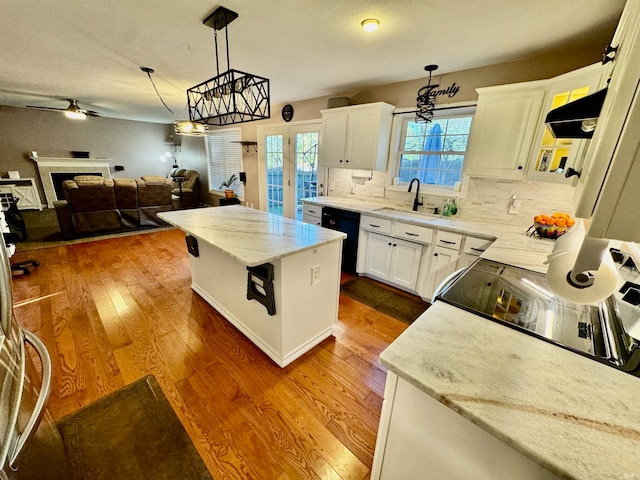 kitchen featuring ceiling fan, dishwasher, a kitchen island, decorative backsplash, and white cabinets