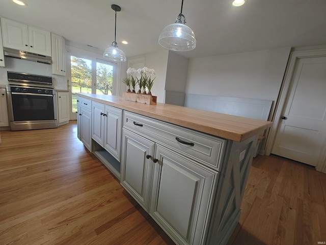 kitchen with white cabinets, light hardwood / wood-style flooring, range, and butcher block counters