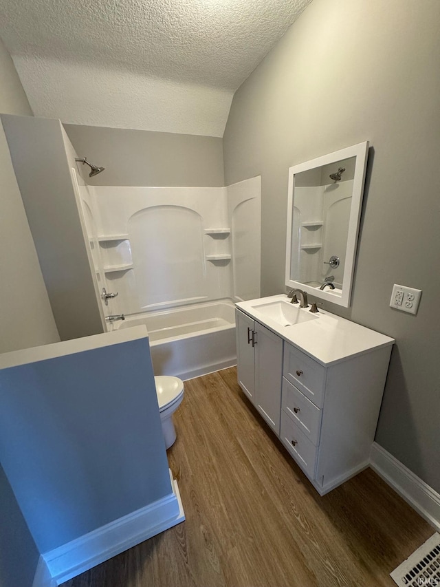 full bathroom featuring toilet, wood-type flooring, vaulted ceiling, washtub / shower combination, and vanity