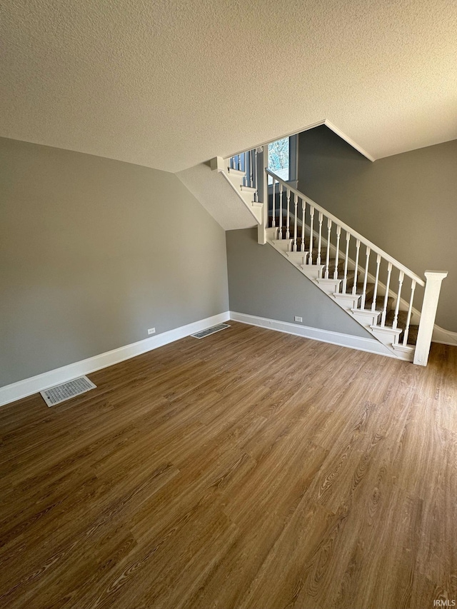 unfurnished living room with hardwood / wood-style flooring and a textured ceiling