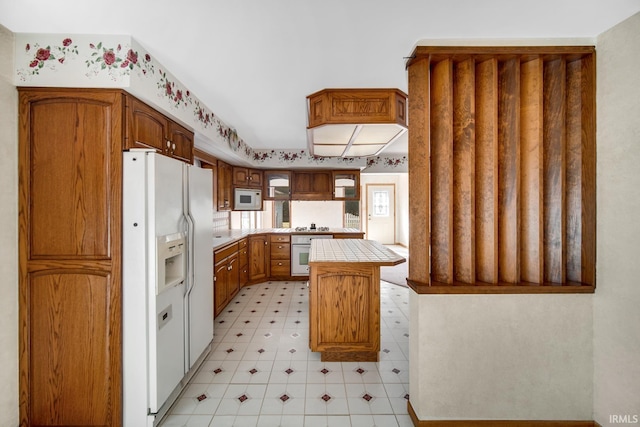 kitchen with tile countertops, white appliances, and a kitchen island