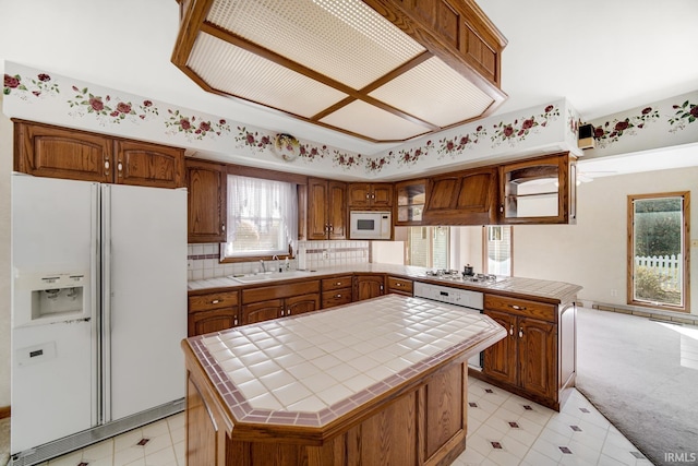 kitchen with decorative backsplash, tile counters, white appliances, and a kitchen island