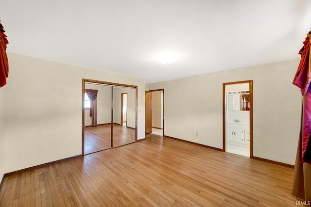 unfurnished bedroom with a closet, light wood-type flooring, and ensuite bath