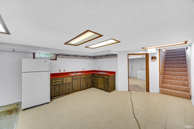 kitchen with sink, white fridge, and a textured ceiling