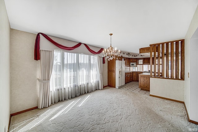 unfurnished dining area featuring light carpet and an inviting chandelier