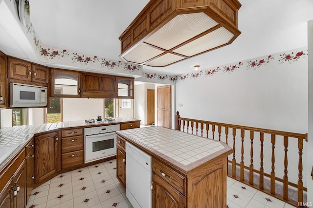 kitchen featuring tile counters, white appliances, and a center island