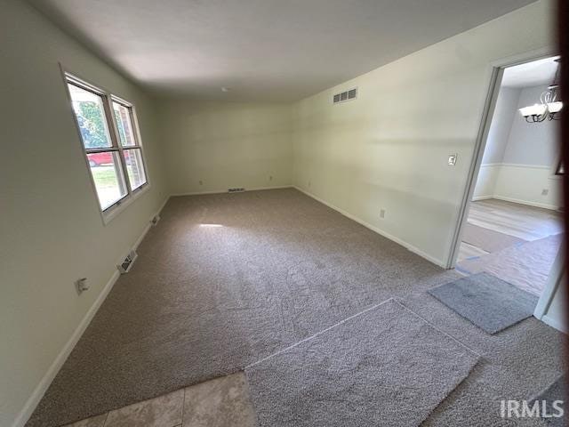 unfurnished room with carpet floors and an inviting chandelier