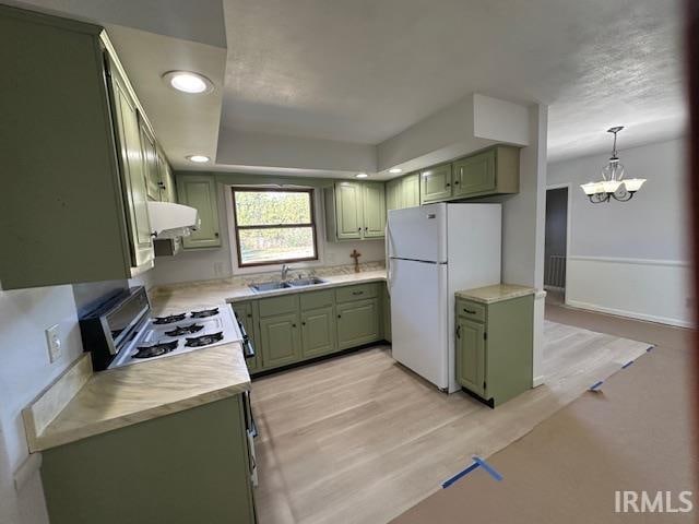 kitchen with light wood-type flooring, white appliances, range hood, green cabinetry, and sink