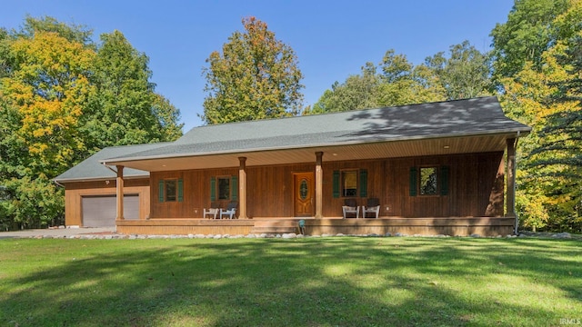 view of front of property featuring a garage, a front lawn, and covered porch