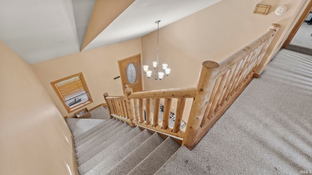 stairs with a notable chandelier, vaulted ceiling, and carpet