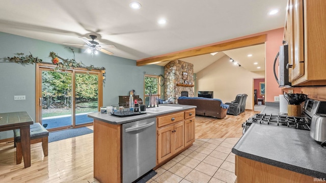 kitchen with ceiling fan, a kitchen island with sink, light hardwood / wood-style flooring, stainless steel appliances, and lofted ceiling with beams