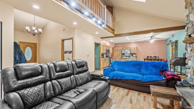 living room featuring ceiling fan with notable chandelier, vaulted ceiling, and light hardwood / wood-style flooring