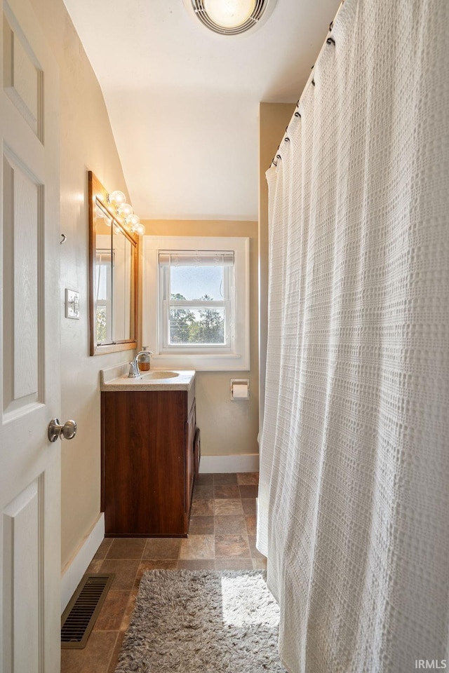 bathroom with walk in shower, vanity, and lofted ceiling