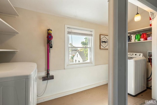 clothes washing area featuring washing machine and clothes dryer and light hardwood / wood-style floors