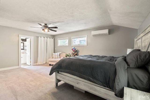 carpeted bedroom with ceiling fan, a wall mounted AC, vaulted ceiling, a textured ceiling, and ensuite bathroom