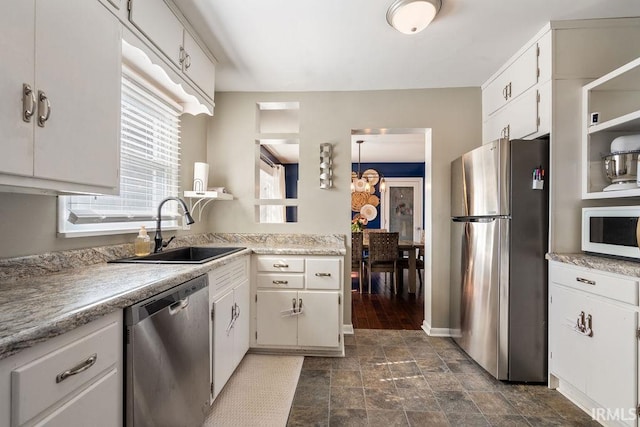 kitchen with appliances with stainless steel finishes, white cabinetry, and sink