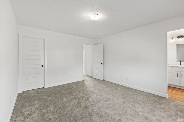 carpeted spare room featuring sink and a textured ceiling