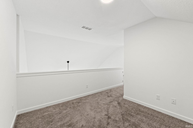 carpeted empty room with vaulted ceiling and a textured ceiling