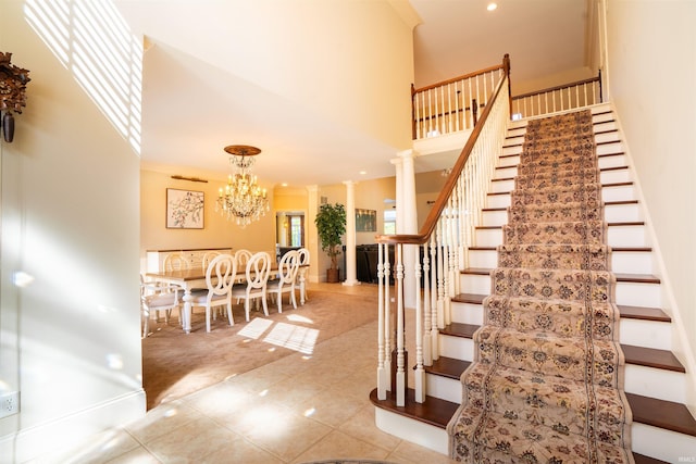 staircase featuring decorative columns, a towering ceiling, and carpet