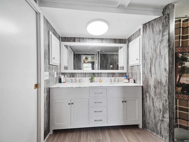 bathroom featuring wood walls, hardwood / wood-style floors, vanity, and beam ceiling