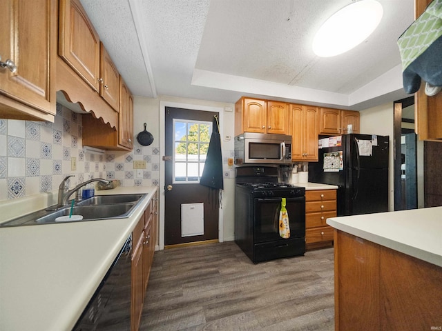 kitchen featuring black appliances, hardwood / wood-style flooring, sink, vaulted ceiling, and a textured ceiling