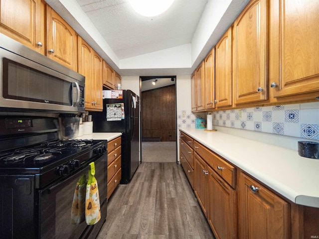 kitchen with lofted ceiling, tasteful backsplash, a textured ceiling, black appliances, and dark hardwood / wood-style flooring