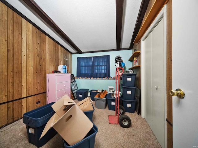 interior space with lofted ceiling with beams, wooden walls, carpet floors, and a textured ceiling