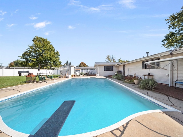 view of pool with a diving board and a patio area