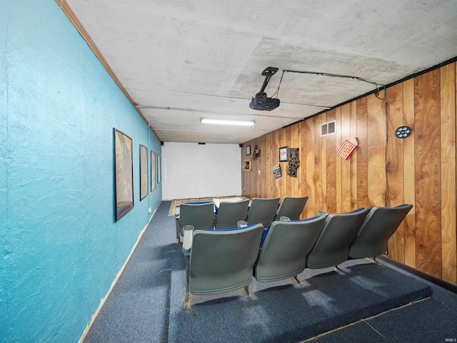 home theater featuring wood walls and dark carpet