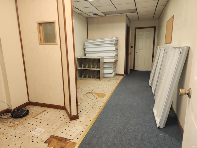 hallway featuring a drop ceiling and light colored carpet