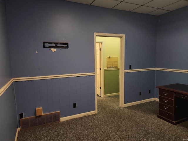 unfurnished office featuring a drop ceiling and dark colored carpet