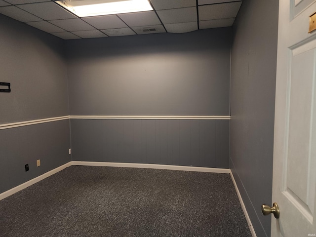 empty room with a drop ceiling and carpet