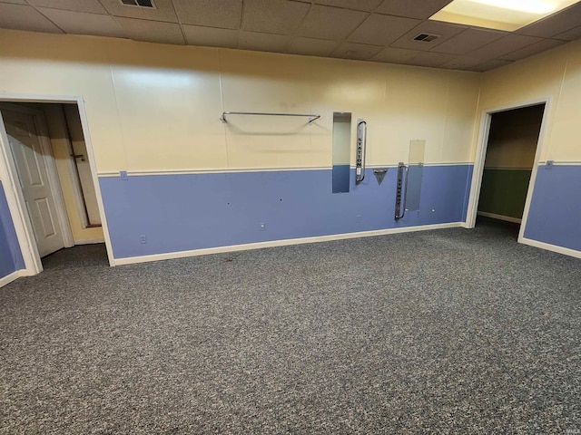 basement with a drop ceiling and dark colored carpet