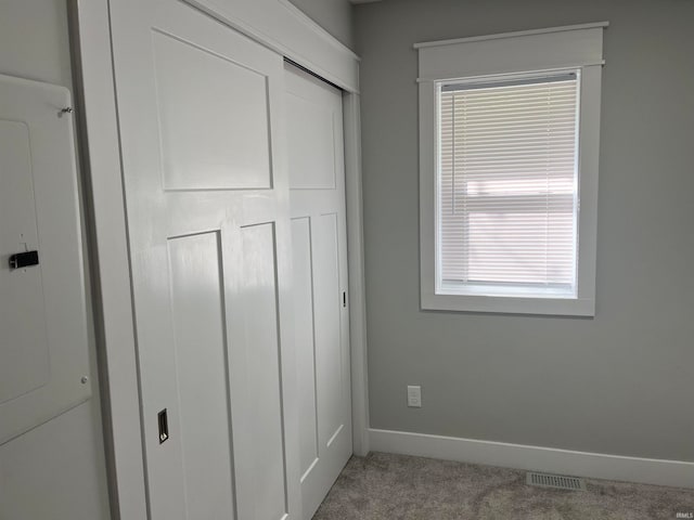 unfurnished bedroom featuring electric panel, a closet, and carpet flooring