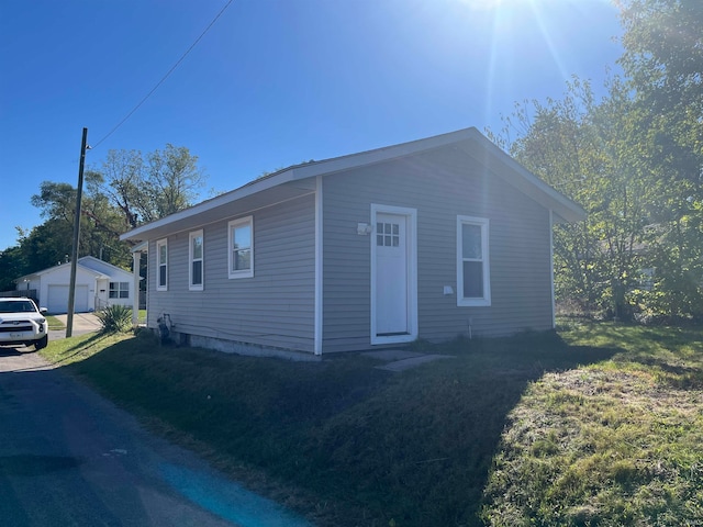 view of front of home featuring a garage, an outdoor structure, and a front lawn