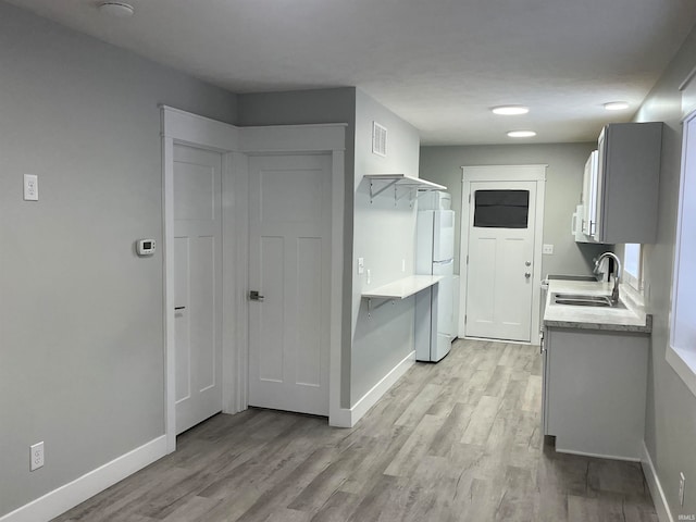 kitchen with sink, light hardwood / wood-style flooring, stove, and white fridge