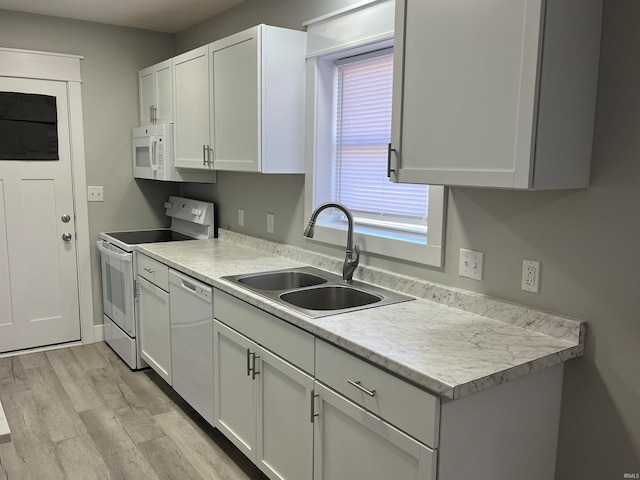 kitchen with light wood-type flooring, white appliances, sink, and white cabinets