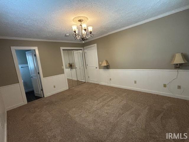 carpeted empty room with crown molding, an inviting chandelier, and a textured ceiling