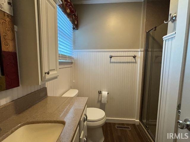 bathroom with wood-type flooring, vanity, toilet, and an enclosed shower