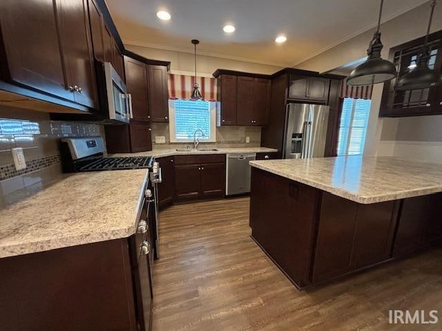 kitchen featuring dark brown cabinetry, stainless steel appliances, tasteful backsplash, hardwood / wood-style flooring, and pendant lighting