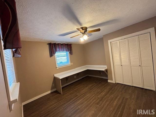 unfurnished bedroom with ceiling fan, a textured ceiling, a closet, and dark hardwood / wood-style flooring